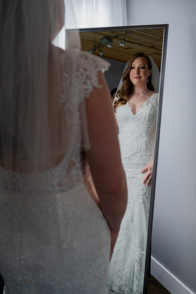 Leah admiring her wedding dress in the mirror.