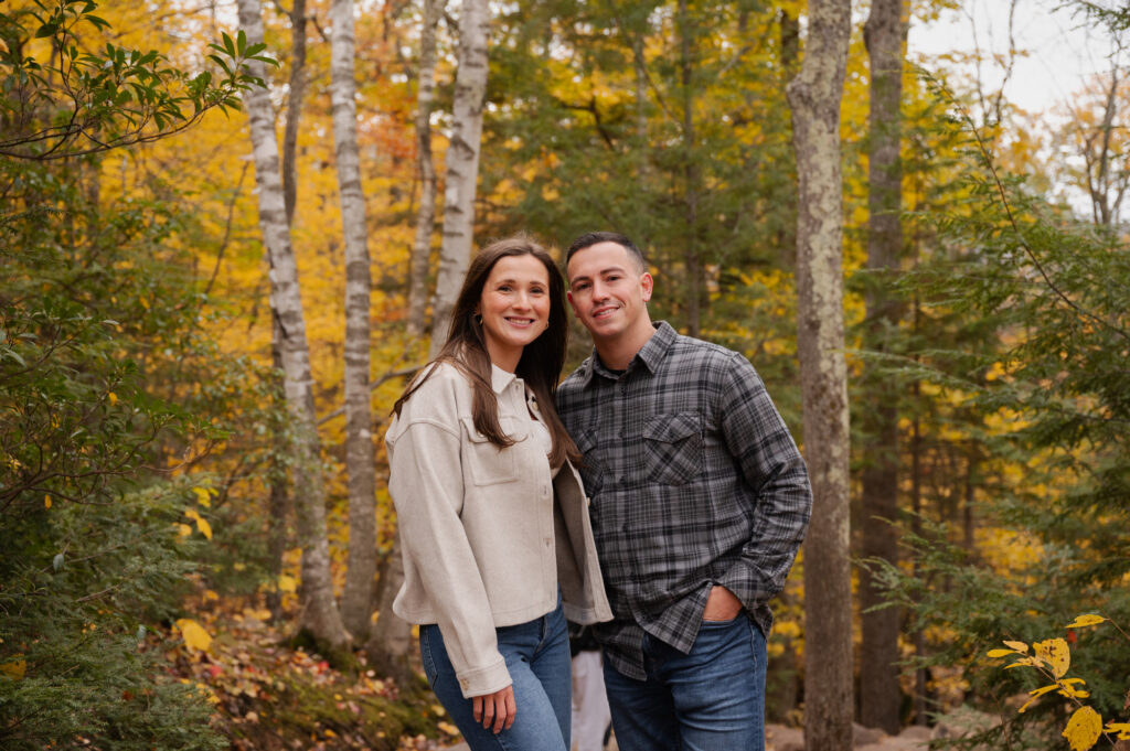 A couple surrounded by the colors of fall leaves during their engagement session in the Catskill Mountains.