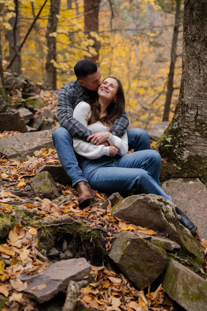 Dolan wrapping Aubrie in his arms at Kaaterskill Falls during their engagement session in the Catskill Mountains.