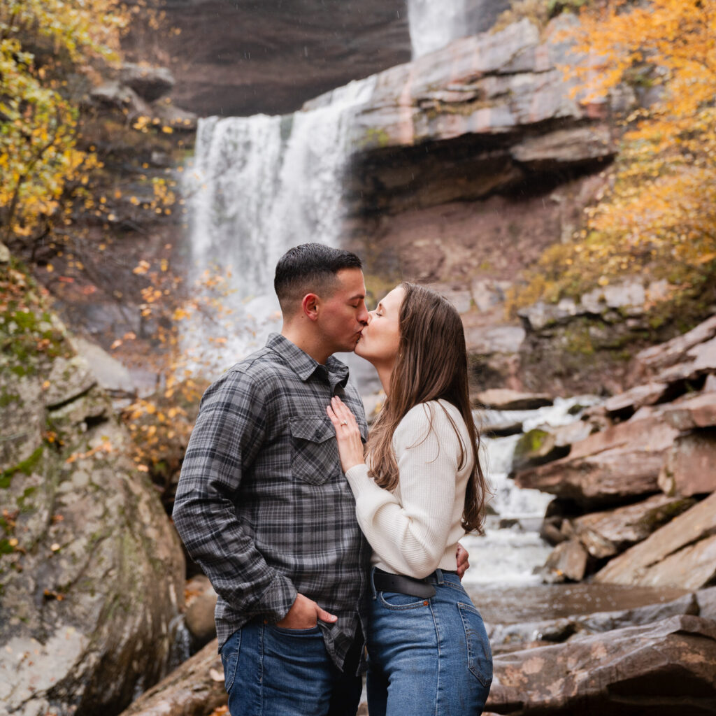 Aubrie and Dolan sharing a kiss just below Kaaterskill Falls during their engagement session in the Catskill Mountains.