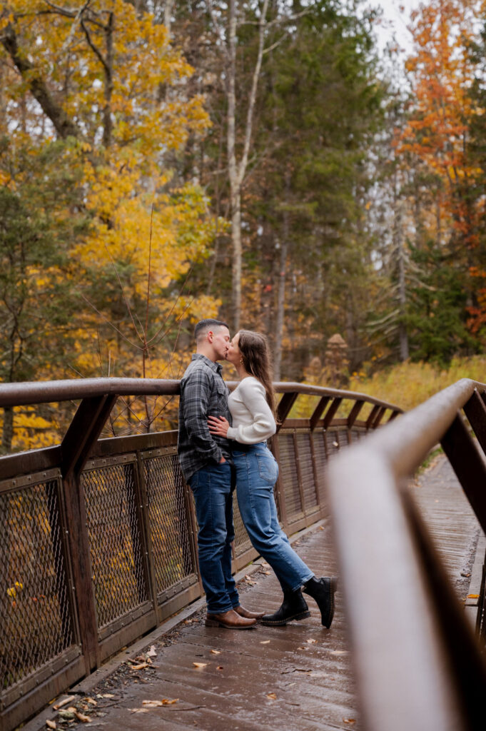 Catskills Wedding Photographer - Aubrie and Dolan sharing a kiss on the bridge at Kaaterskill Falls during their engagement session in the Catskill Mountains.