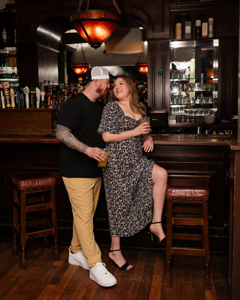 A couple at the bar at Harvey's Pub in downtown Saratoga Springs during their engagement photos with Austin Ryan Photo.