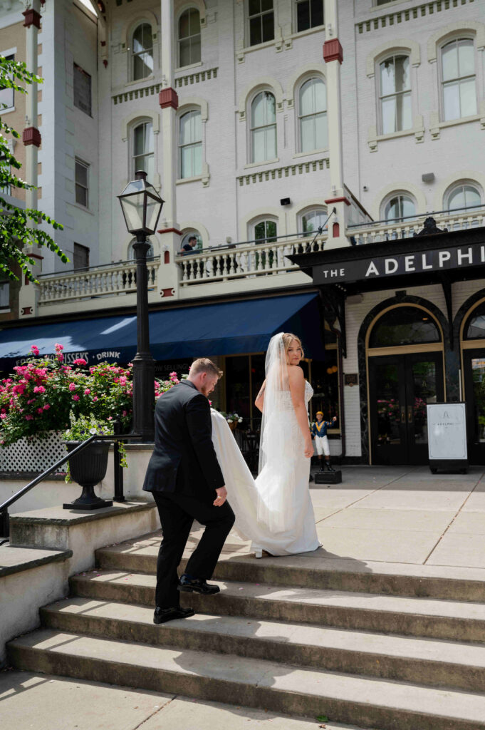 The groom helping the bride up the stairs outside of The Adelphi Hotel.