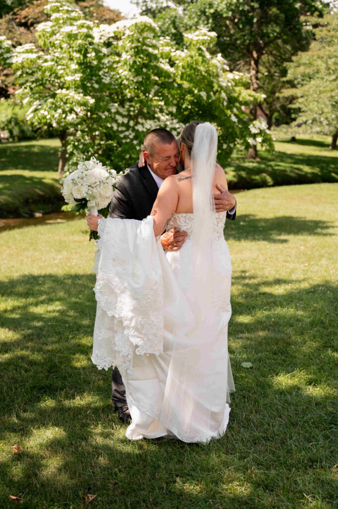 The bride and her dad share a hug after a private first look in Congress Park outside of the Canfield Casino.