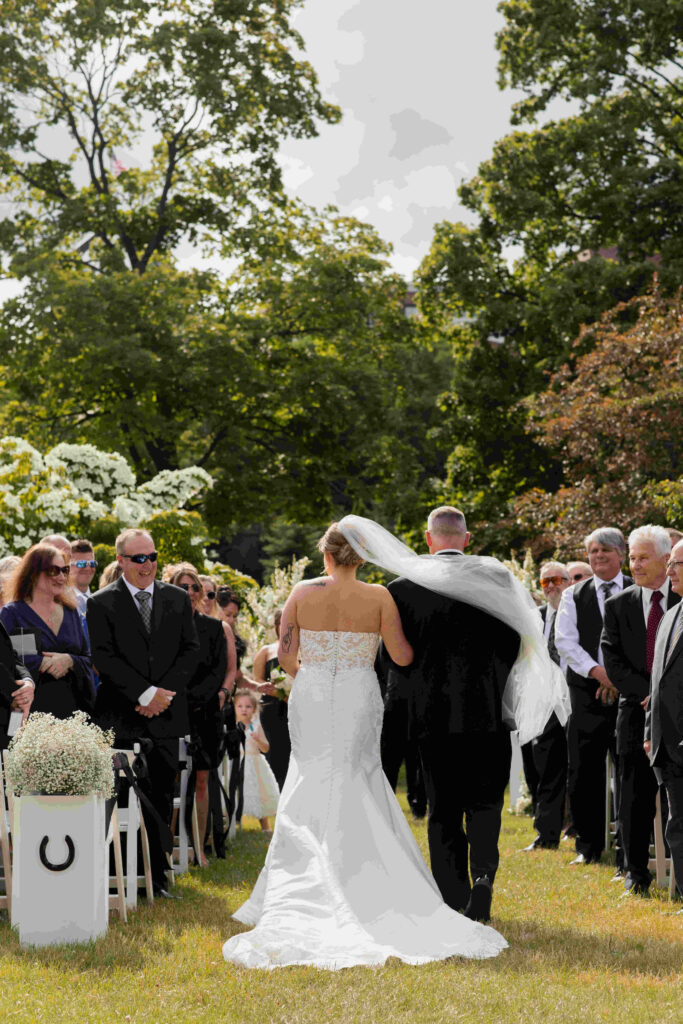 The bride's step dad walking her down the aisle during her wedding in Congress Park outside of the Canfield Casino.