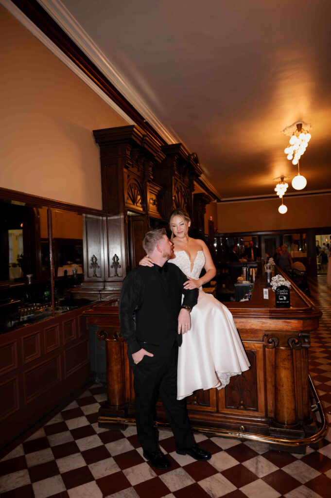 The bride and groom posing for a photo on the bar inside the Canfield Casino in Saratoga Springs, New York.