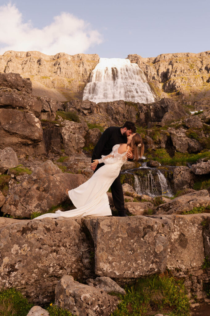 The bride and groom sharing a kiss at Dynjandi Waterfall for their Iceland destination wedding photos.