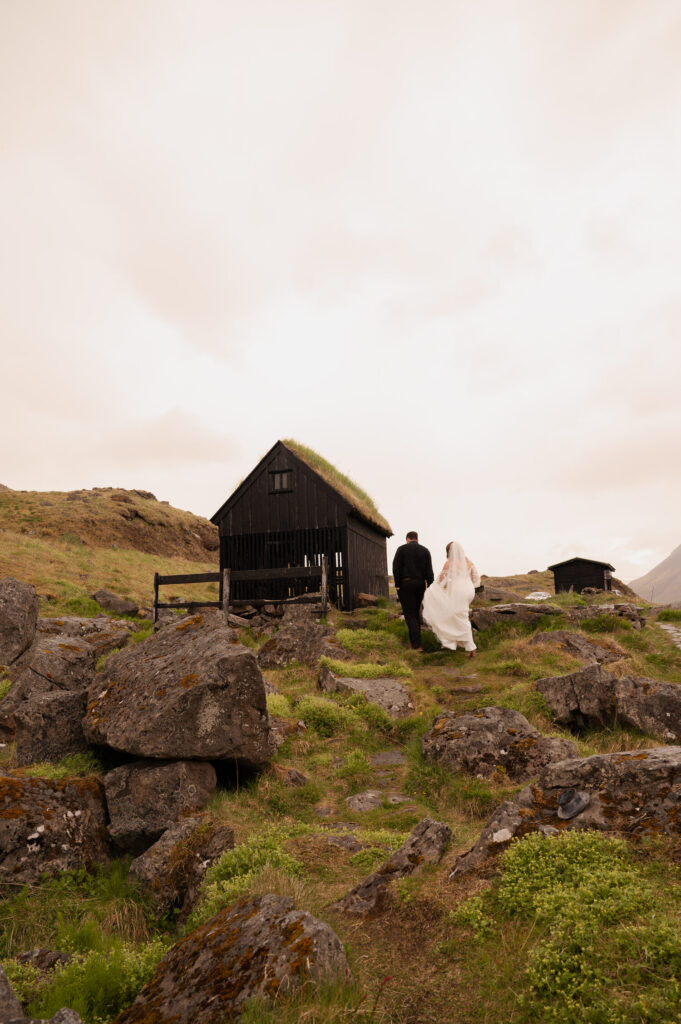 A candid of the bride and groom beside a fishing hut overlooking the Westfjords of Iceland during their Iceland destination wedding.
