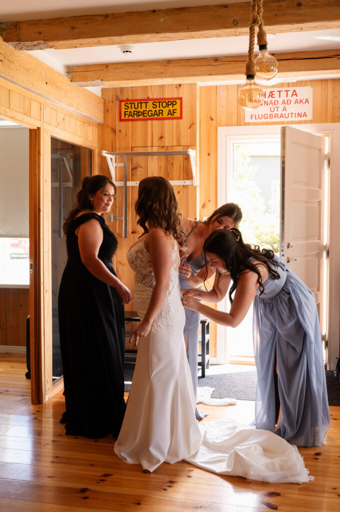 The bridesmaids helping the bride into her dress at an Airbnb in Ísafjörður.