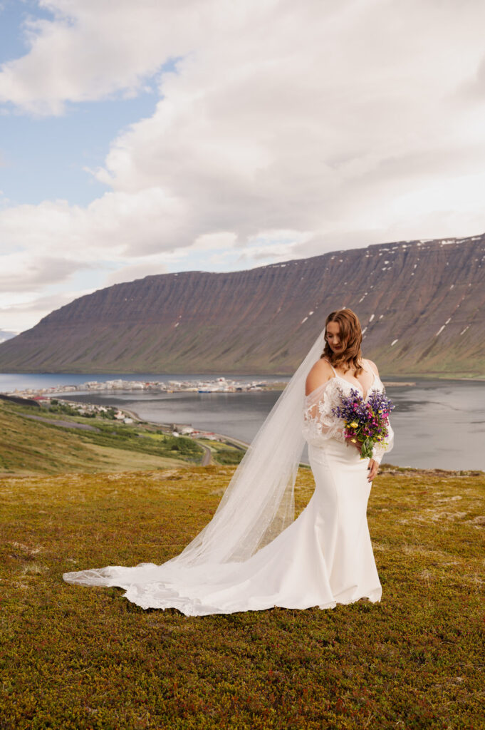 A portrait of the bride during her Iceland destination wedding with her veil blowing in the wind overlooking the city of Ísafjörður.